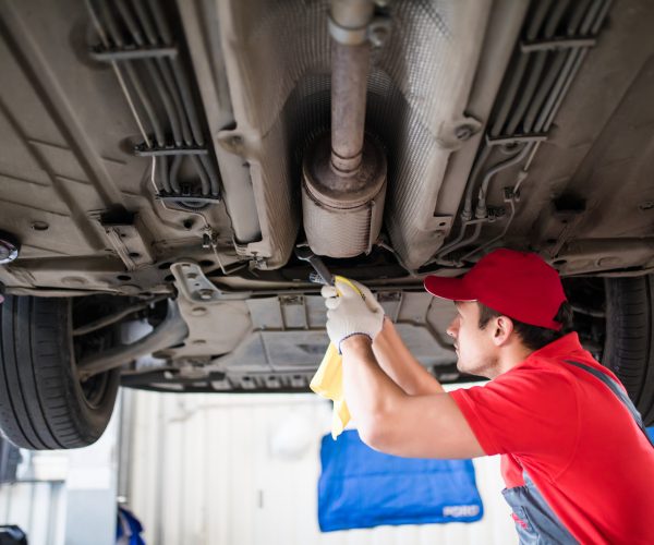 car mechanic with spanner tighten car suspension detail of lifted automobile at repair station